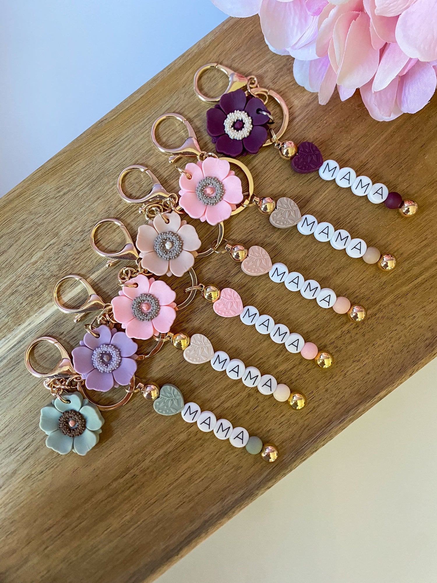 A collection of keychains with floral designs and the word 'Mama' inscribed on a wooden surface.