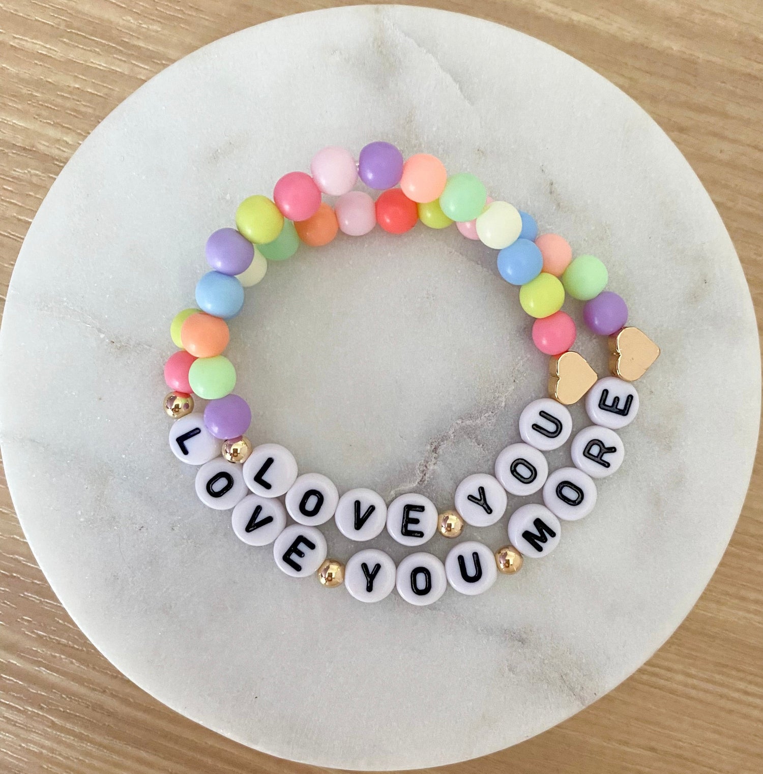 A multicolored bracelet with acrylic beads, gold plated beads, and gold filled beads, featuring the words 'LOVE YOU' and 'LOVE YOU MORE'.