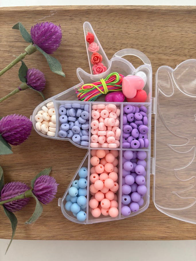 Unicorn-shaped bead organizer with colorful beads on a wooden surface