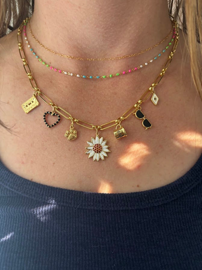 Necklace with various charms including a flower pendant on a person wearing a dark blue top.
