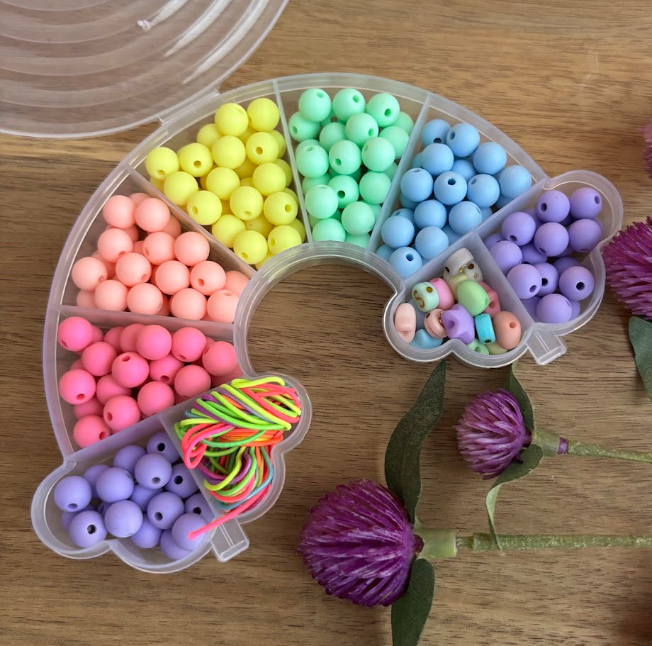 Colorful beads in a clear plastic organizer on a wooden surface