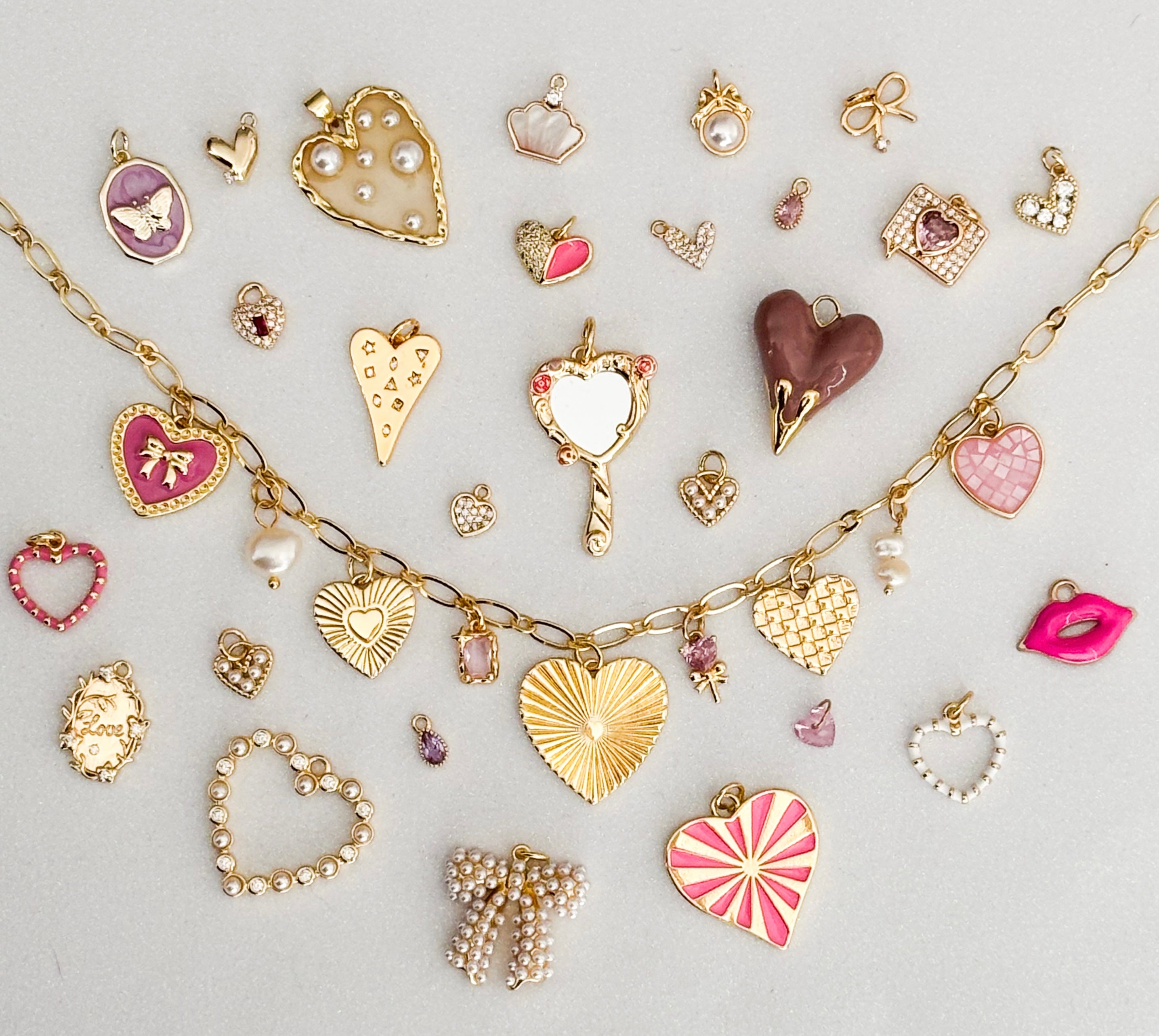 Collection of heart-shaped jewelry charms on a light gray background