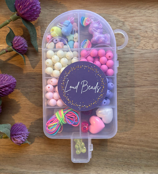 Clear popsicle shaped container with colorful beads on a wooden surface