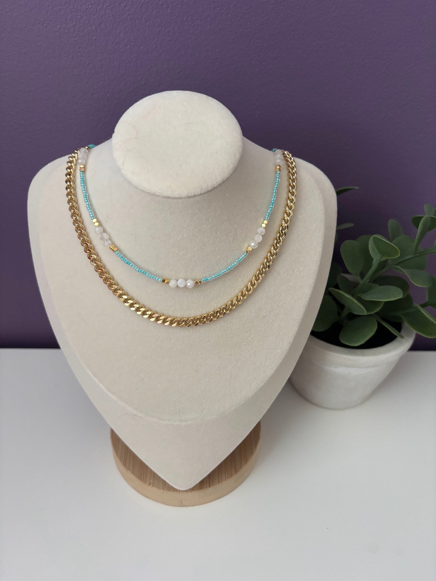 Necklace set on a mannequin bust with a purple background