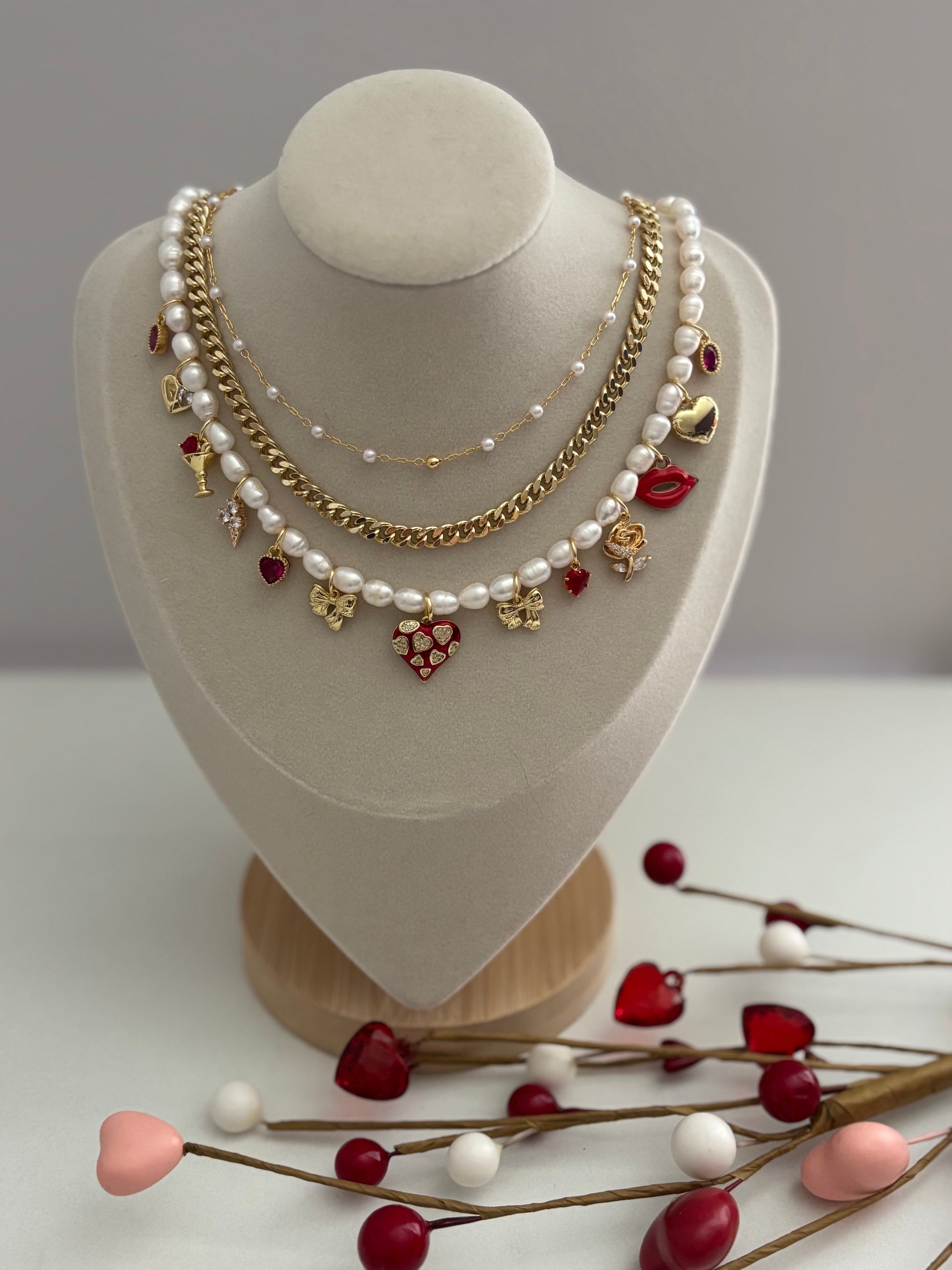 Necklace with pearls and charms on a mannequin bust with decorative branches on a light background
