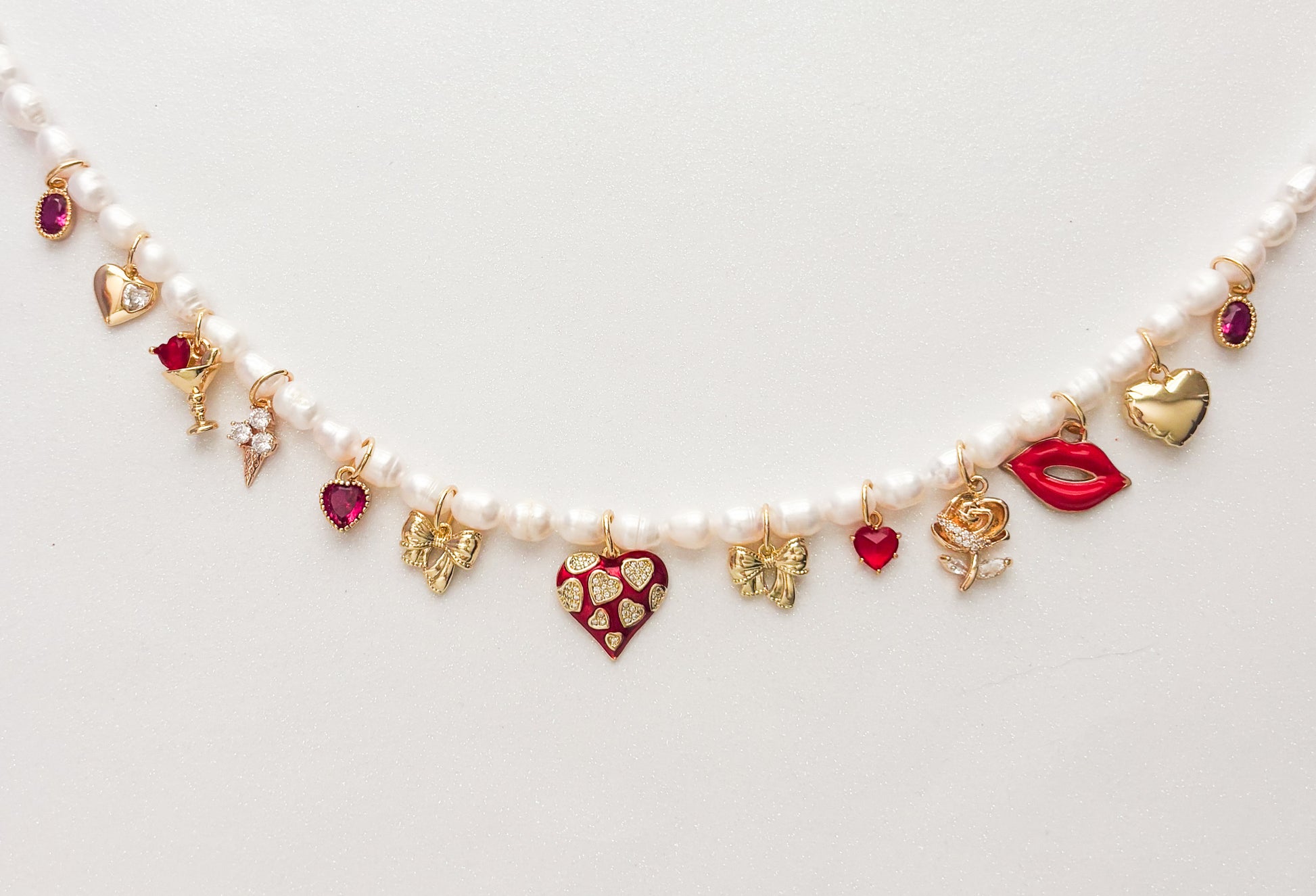 Pearl necklace with heart-shaped charms on a light gray background