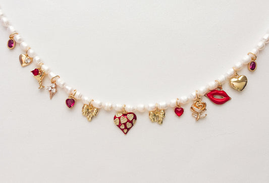 Pearl necklace with heart-shaped charms on a light gray background