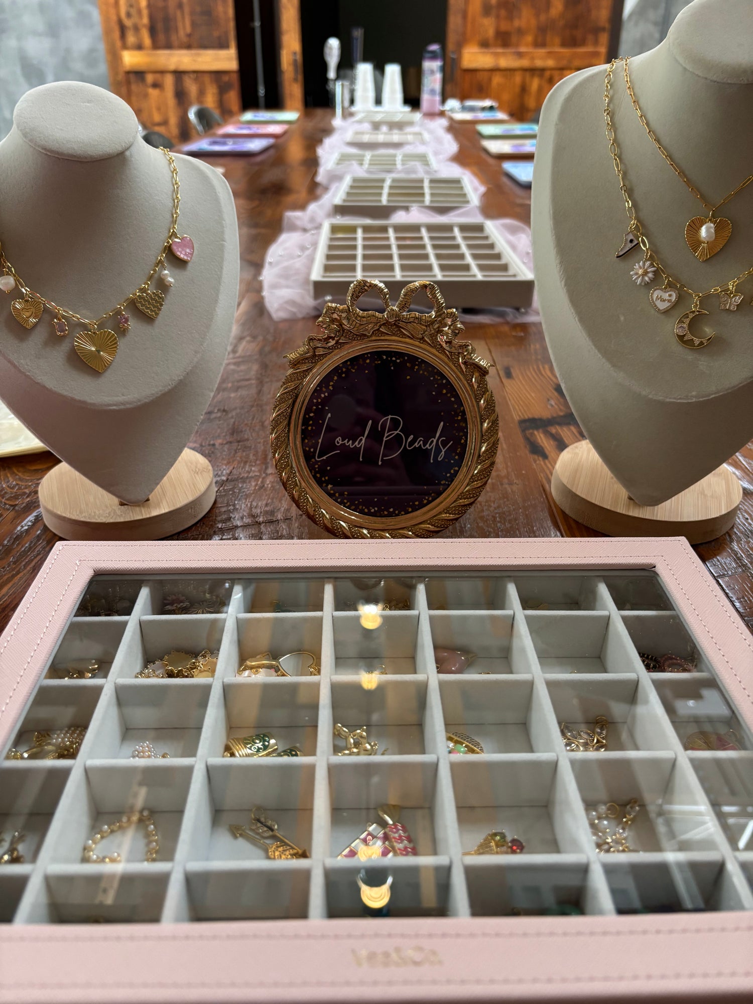 Jewelry display with necklaces on mannequins and an open jewelry box on a wooden table.
