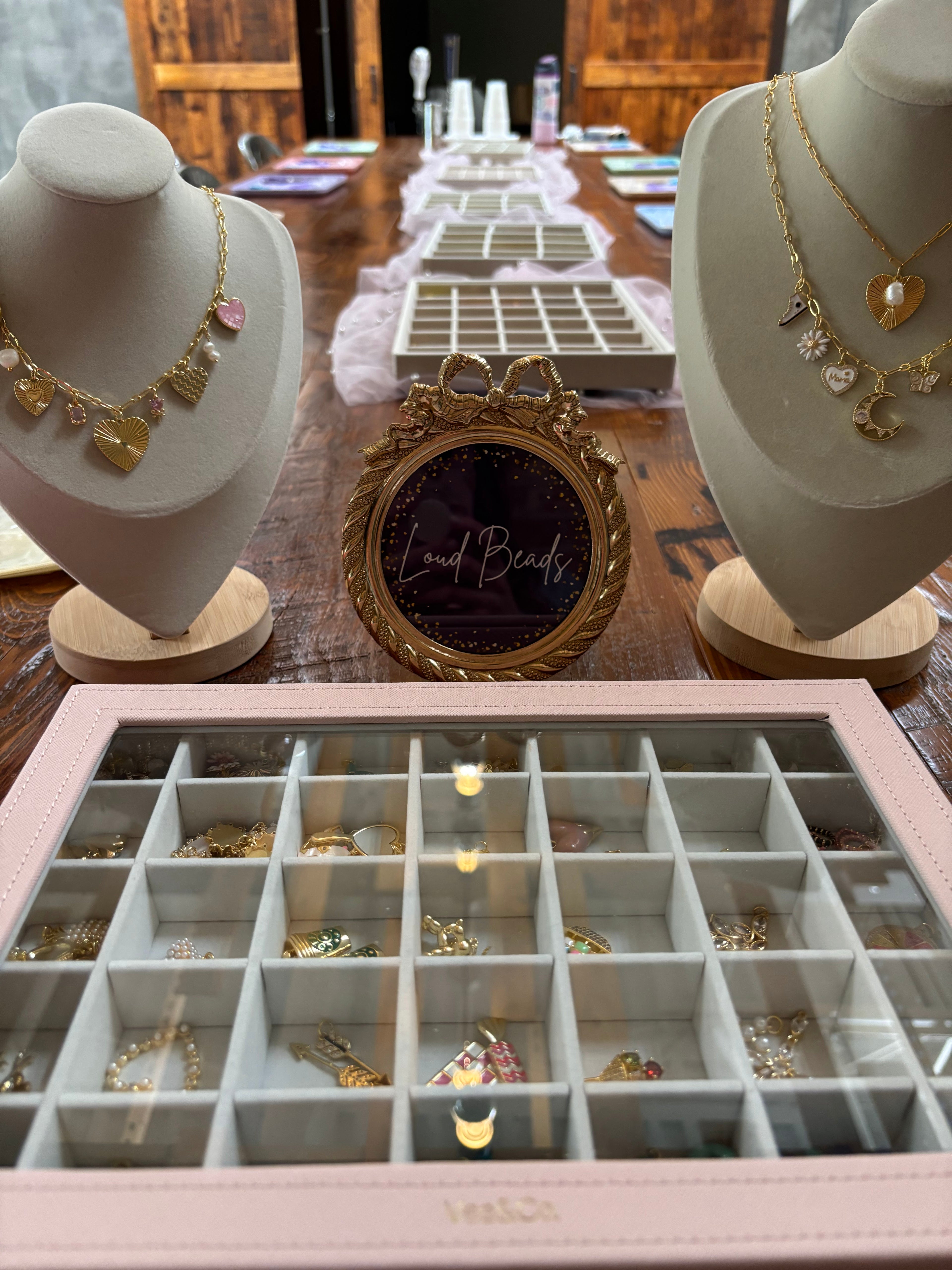 Jewelry display with necklaces on mannequins and an open jewelry box on a wooden table.