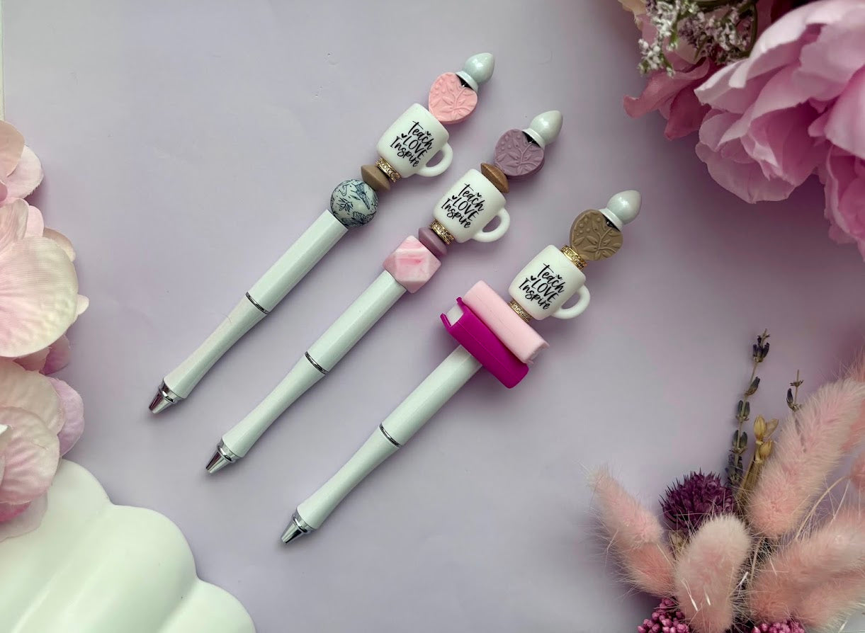 Three decorative pens with unique tips on a light purple background with flowers.
