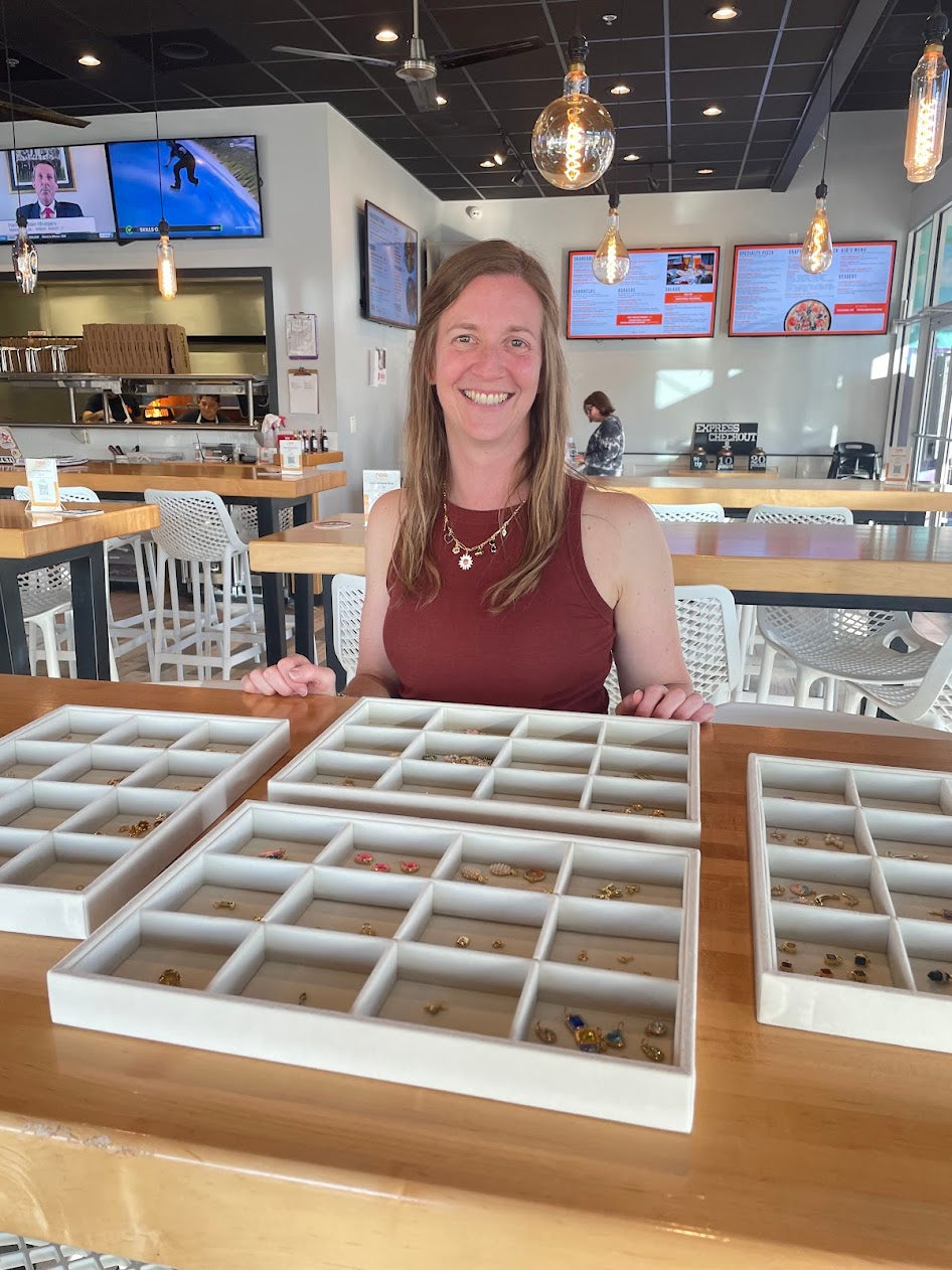 Woman standing behind a counter with jewelry display trays in a store setting